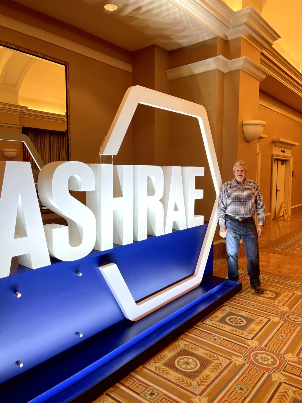 Man sending in front of large 3D sign for ASHRAE