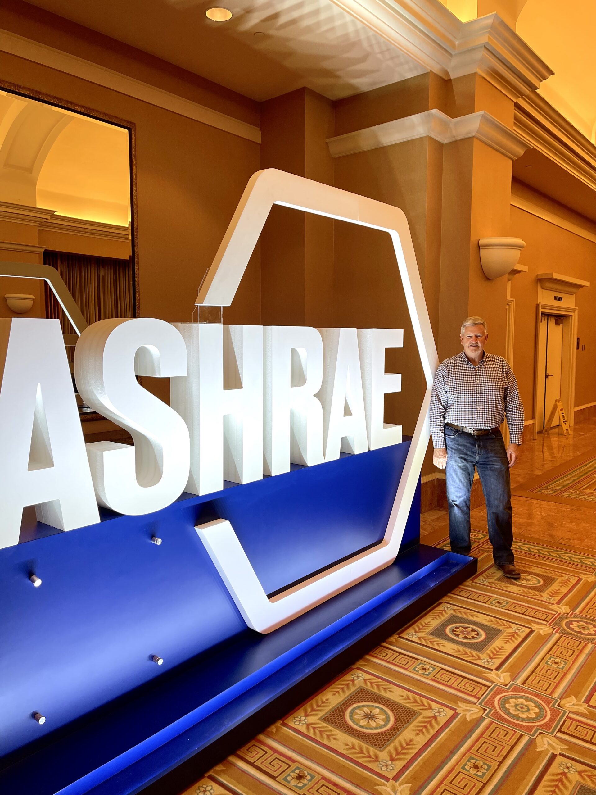 Man sending in front of large 3D sign for ASHRAE